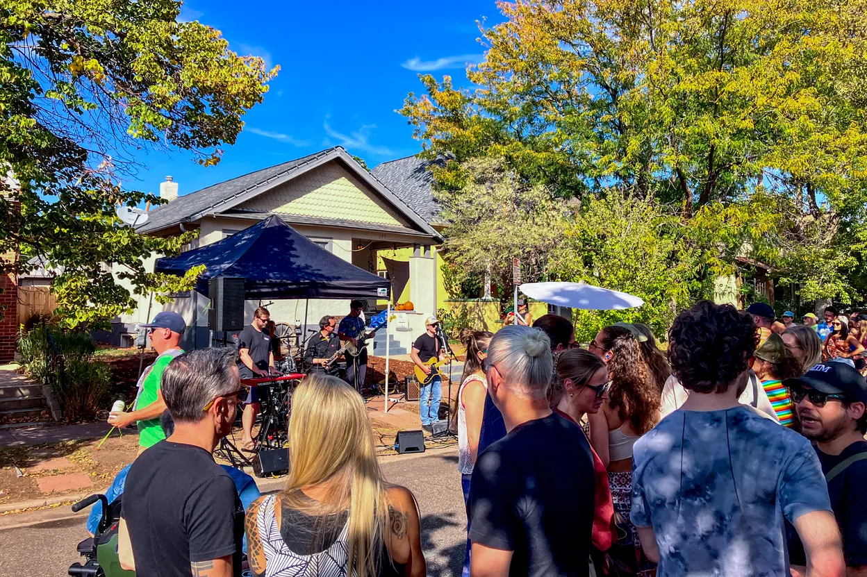 A crowd fills a street in Baker as Late Nite Takeout plays on a front porch